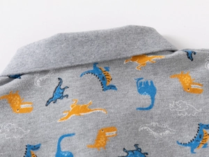 Close-up of boys gray polo shirt with colorful dinosaur print and ribbed collar detail