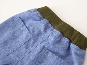 Detail view of boys' light blue shorts featuring elastic waist and military green belt