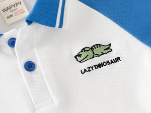 Détail d'un polo pour enfant avec broderie dinosaure et col côtelé bicolore