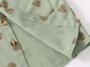 Close-up of cotton children shirt featuring cute bear prints and amber textured buttons