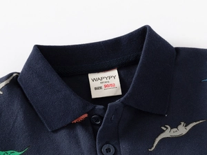 Détail du col polo bleu marine avec imprimé dinosaure et étiquette de taille
