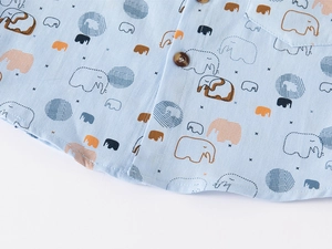 Detail of light blue boys' shirt featuring cartoon elephant print and wood texture buttons