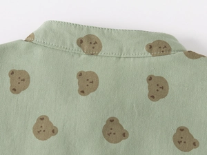 Detail of baby boy cotton shirt with brown cartoon bear prints and neat stitching