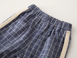 Detail of blue and white plaid cotton shorts with elastic waist and side tape trim