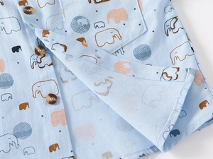 Detail of baby boy cotton shirt with orange elephant print and wood texture buttons