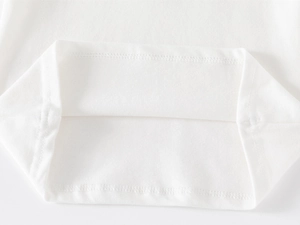 Détail de la maille piquée en coton blanc avec une couture d'ourlet à double aiguille