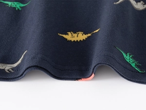 Détail de la couture double aiguille et imprimés dinosaures sur polo bleu marine