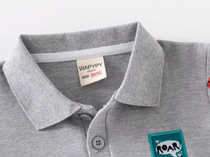 Detail of gray boys polo shirt with dinosaur roar embroidery and cotton pique texture