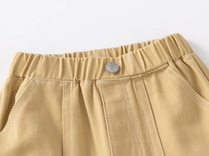 Detail of kids twill cotton trousers featuring elastic waistband and metal button
