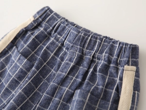 Detail of blue plaid shorts featuring elastic waistband and side webbing decoration