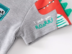 Detail of kids polo shirt sleeve with red dinosaur pattern and green 3D dorsal fins