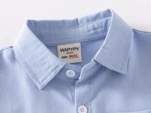 Close-up of baby boy light blue cotton shirt collar with brand label and white button