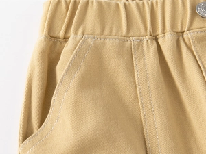 Detail view of elastic waist and metal jeans button on khaki cotton pants for boys