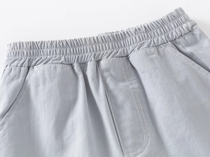 Détail d'un short en coton gris clair pour garçon avec taille élastique et poches latérales