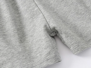Gros plan détaillé montrant les coutures renforcées d'un short en coton gris pour enfant