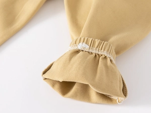 Detail of children's ginger cotton trousers showing elasticated cuffs and twill texture