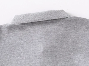 Close-up of grey pique knit cotton fabric on a boys polo shirt showing breathable texture