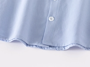 Detail of light blue cotton shirt showing white buttons and neat hem stitching