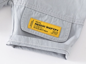 Détail d'un short en coton gris pour garçon montrant une poche avec étiquette brodée