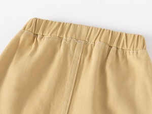 Detailed macro of khaki cotton twill pants featuring an elastic waistband and dual stitching