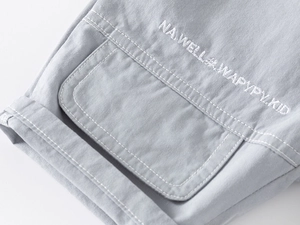 Vue détaillée de la broderie blanche et de la double couture sur le short pour garçon