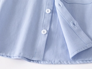 Close-up of light blue cotton fabric texture with white button and precise stitching details