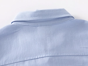 Macro detail of a light blue cotton twill kids shirt collar with premium stitching