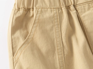 Detail of khaki cotton shorts showing elastic waistband and stitching on side pockets