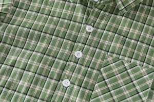 Close-up of green plaid cotton shirt with white buttons and a functional chest pocket
