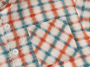 Close-up detail of boy's plaid shirt showing the chest pocket and stitching textures