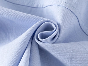 Close-up of light blue kids' shirt fabric showing refined cotton blend weave texture