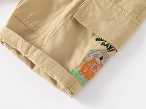 Detail of khaki cotton shorts featuring flap pocket and 'GOOD DAY' cartoon embroidery