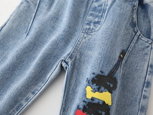 Detail view of light blue denim fabric with colorful abstract tower prints on the leg