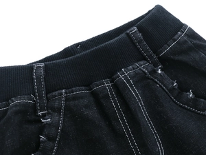Detail of kids black denim jeans featuring ribbed elastic waistband and contrast stitching