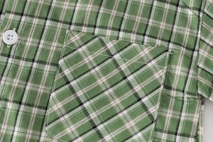 Close-up of green plaid kids shirt showing texture, square pocket and white button detail