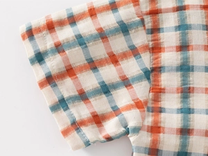 Detailed close-up of orange and blue plaid cotton fabric texture and sleeve stitching