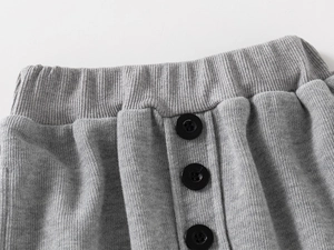Detailansicht hellgraue Strickhose mit Rippstrickbund und drei schwarzen Knöpfen