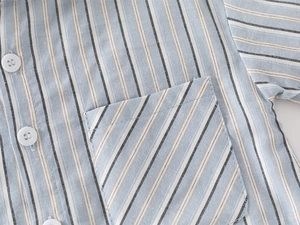 Détail d'une chemise rayée pour garçon avec poche de poitrine et boutons blancs