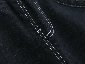 Detail of white contrast stitching and durable black denim fabric texture for kids pants