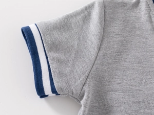 Detail of grey polo shirt sleeve with navy and white striped ribbed cuffs and pique fabric