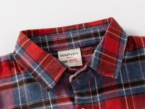 Détail du col d'une chemise à carreaux rouge et bleu montrant la texture et l'étiquette