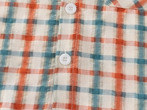 Detailed macro view of the plaid fabric pattern and white resin buttons on the boy shirt