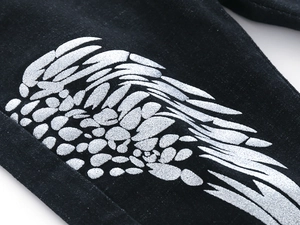 Close-up of silver glitter wing print on black fabric of children denim pants
