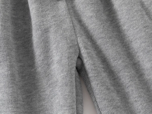 Detailansicht der grauen Strickstruktur und der präzisen Nähte an der Kinderhose im Makro