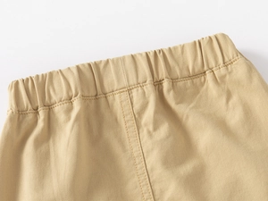 Close-up of elastic waistband on beige boys cotton shorts with neat reinforced stitching