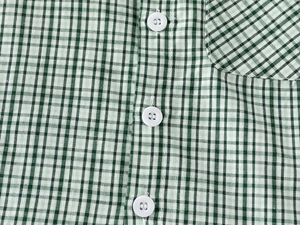 Close-up of green gingham check fabric with white buttons and a neat pocket detail