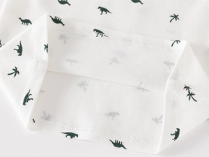 Close-up of double-stitched hem on white cotton kids polo shirt with dinosaur print
