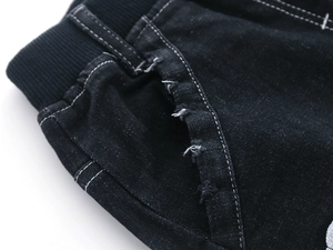 Detailed close-up of kids black denim jeans with elastic waist and distressed pocket design