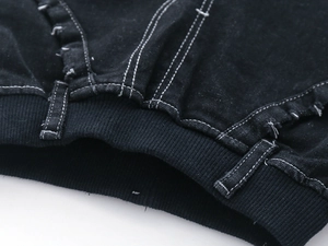 Detail of black denim jeans featuring elastic ribbed waistband and white contrast stitching