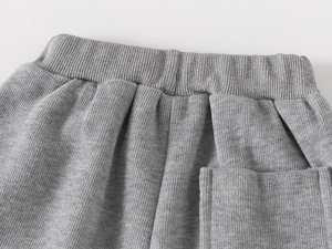 Detail der grauen Jungen-Sweatpants mit elastischem Bund und aufgesetzter Tasche vorne